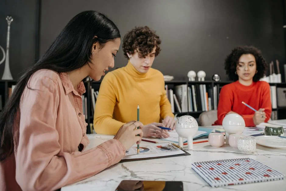 A creative workspace featuring UI design plans, pencils, a smartphone, and other office tools.